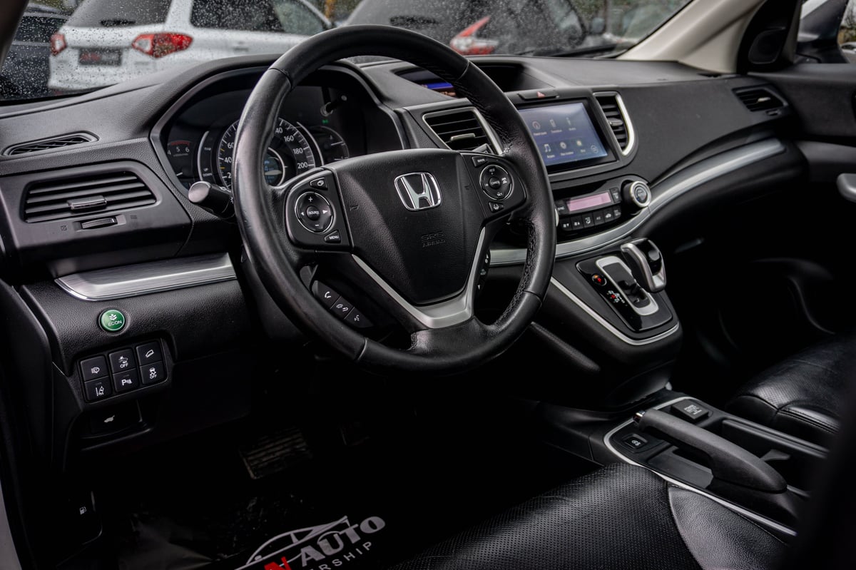 Interior view of Honda vehicle dashboard, steering wheel, and center console with black leather seats and modern infotainment system