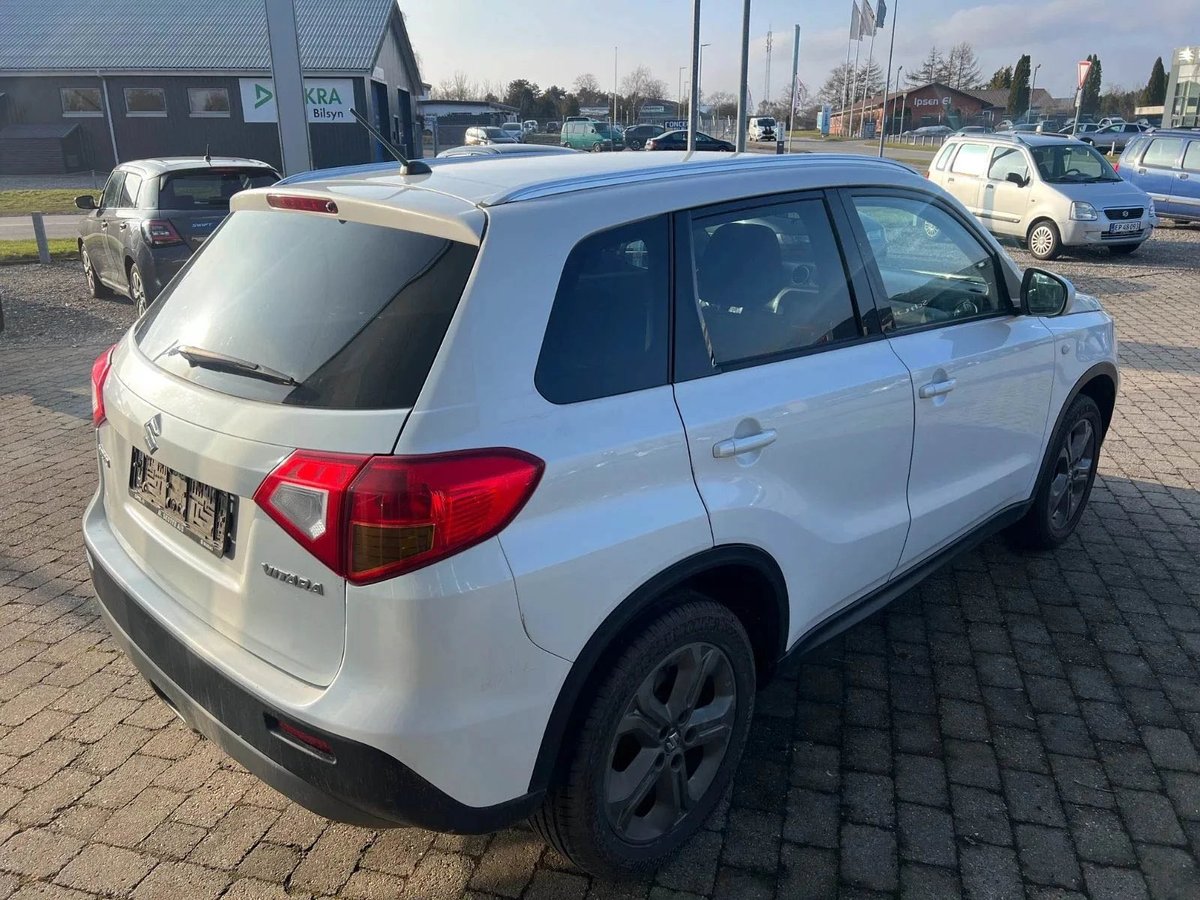 White compact SUV parked on brick pavement in a car dealership lot with other vehicles visible in background