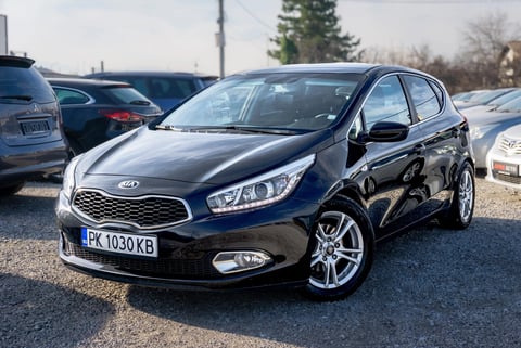 Black Kia Ceed compact car parked in dealership lot with other vehicles visible in background