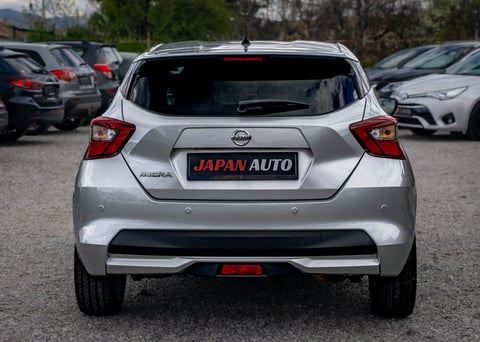 Silver Nissan compact SUV rear view in parking lot with Japan Auto dealership plate