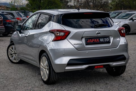 Silver Nissan hatchback with Japan Auto license plate displayed in a car lot with other vehicles