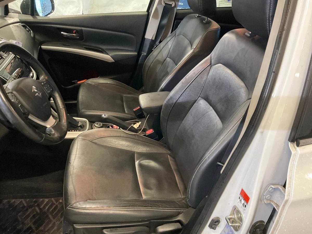 Interior of a car showing front seats with dark gray upholstery, steering wheel, and dashboard visible through the open drivers side door