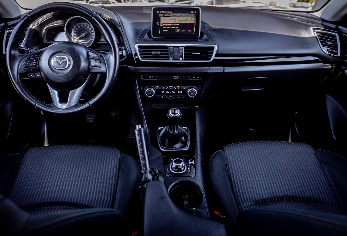 Interior dashboard and steering wheel of a modern Mazda vehicle with blue ribbed seats and touchscreen display