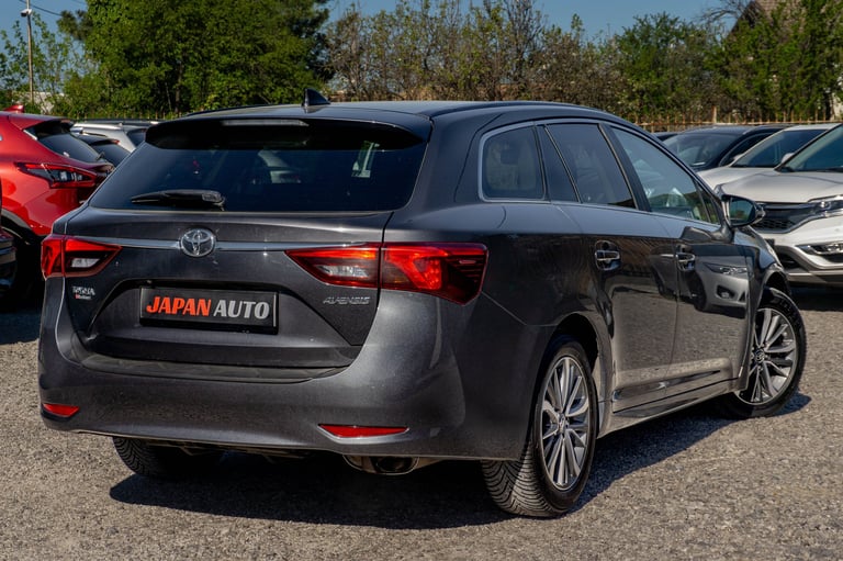 Black Toyota wagon parked in a car lot with other vehicles visible in the background