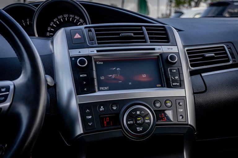 Close-up of car dashboard interior showing steering wheel, digital display screen, and center console controls