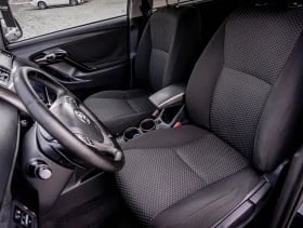 Modern car interior showing black leather seats, steering wheel, and dashboard with center console