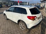 White compact SUV parked on brick pavement at a car dealership with showroom buildings in background
