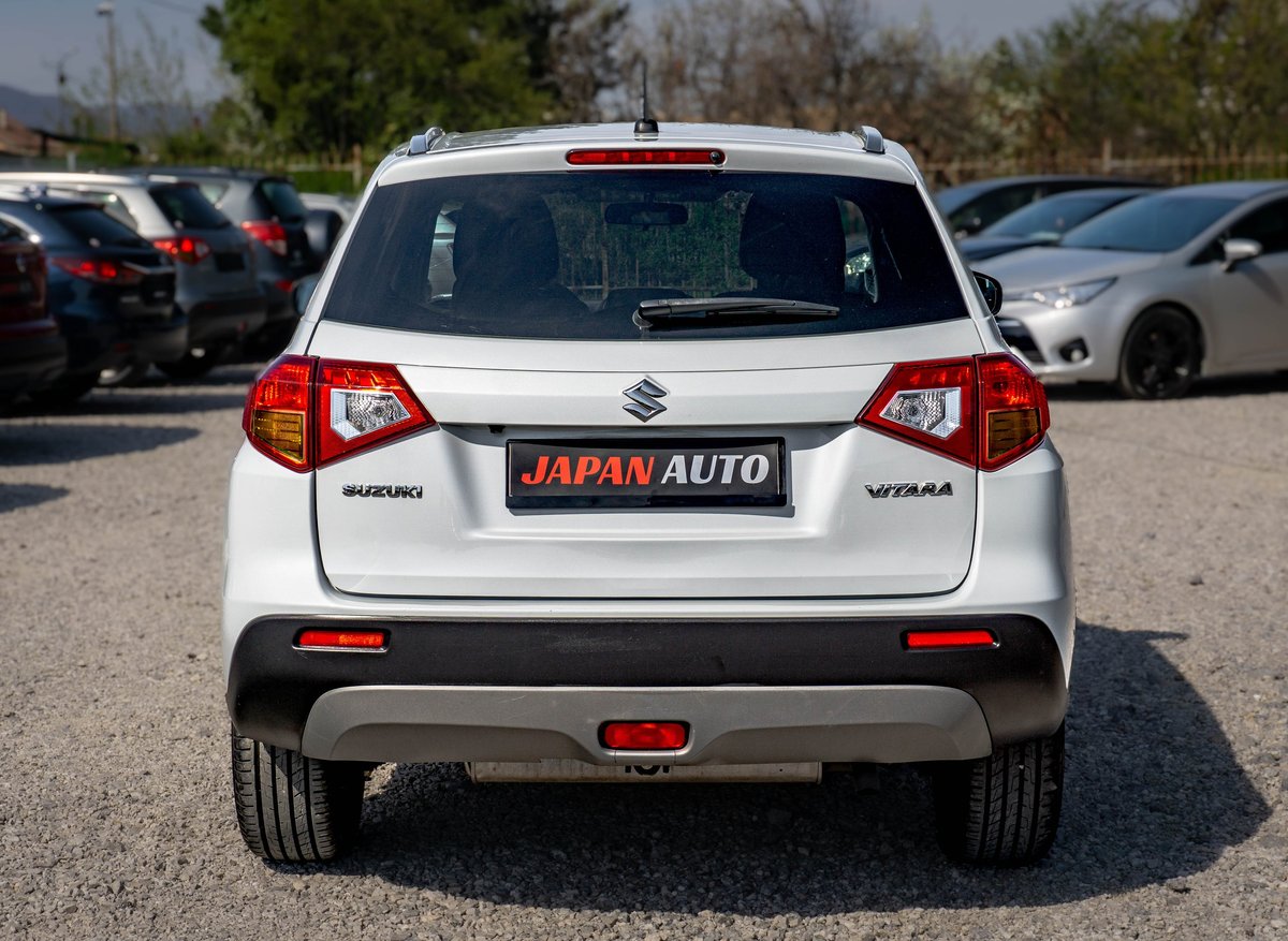 White Suzuki compact SUV with Japan Auto dealer plate, rear view in parking lot
