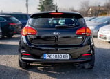 Black Kia hatchback car photographed from behind in a parking lot, showing rear lights and license plate