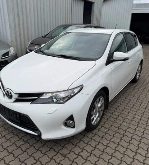 White Toyota Auris hatchback viewed from rear in a parking lot with other cars
