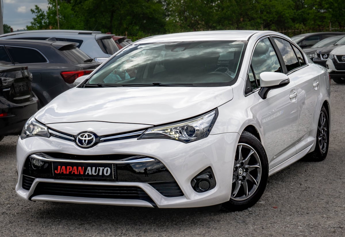 White Toyota sedan parked in a lot with other vehicles visible in the background
