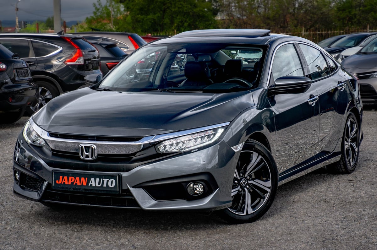 Silver Honda Civic parked in a lot with JAPAN AUTO dealership plate visible on front