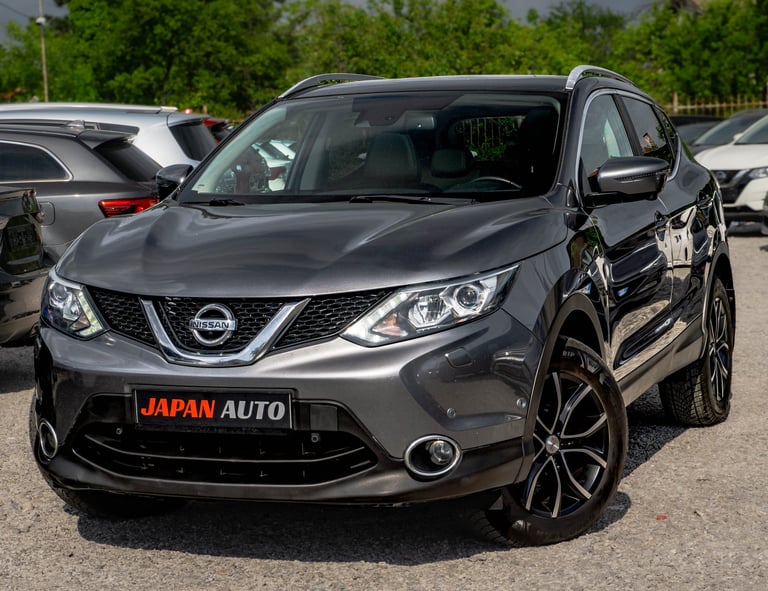 Front view of gray Nissan Qashqai SUV at car dealership with JAPAN AUTO sign on lot