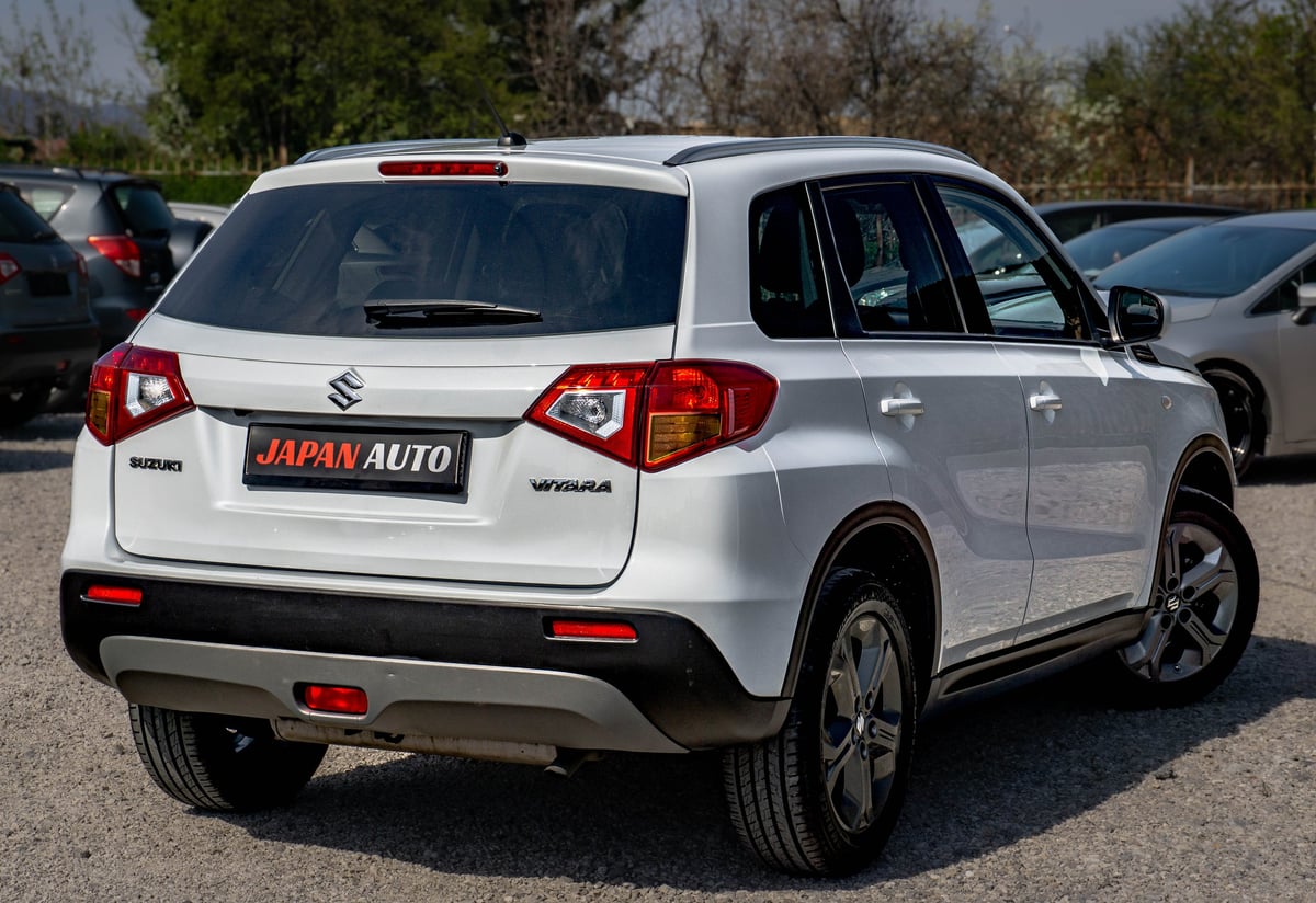 White Suzuki Vitara SUV parked in a lot with Japan Auto dealership branding on the rear
