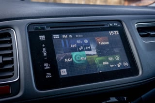 Car dashboard with touchscreen display showing navigation map, FM radio at 81.6, and time 15:22