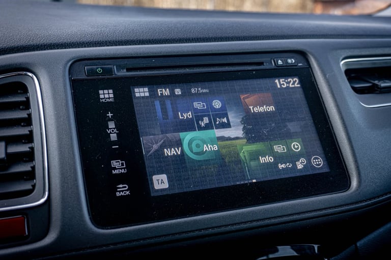 Car dashboard with touchscreen display showing navigation map, FM radio at 81.6, and time 15:22