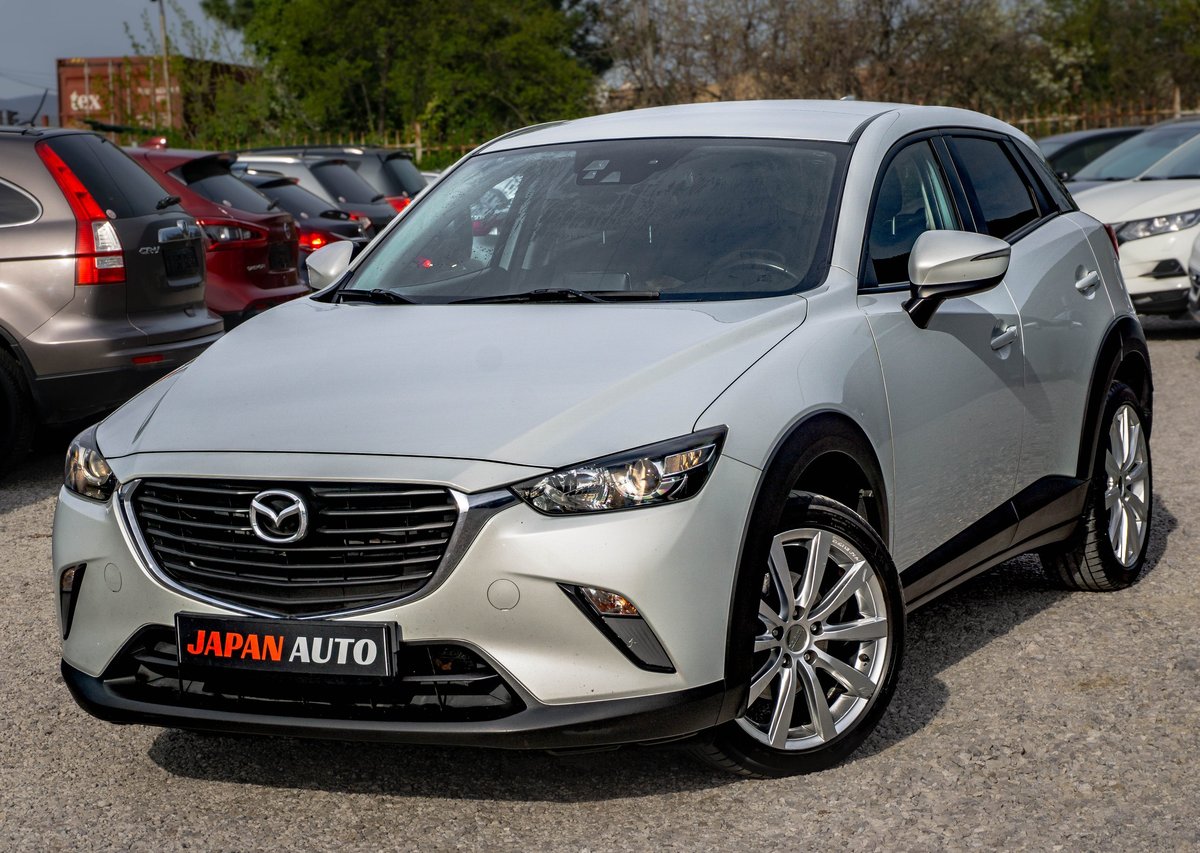 White Mazda CX-3 compact SUV displayed at a car dealership lot with other vehicles in background