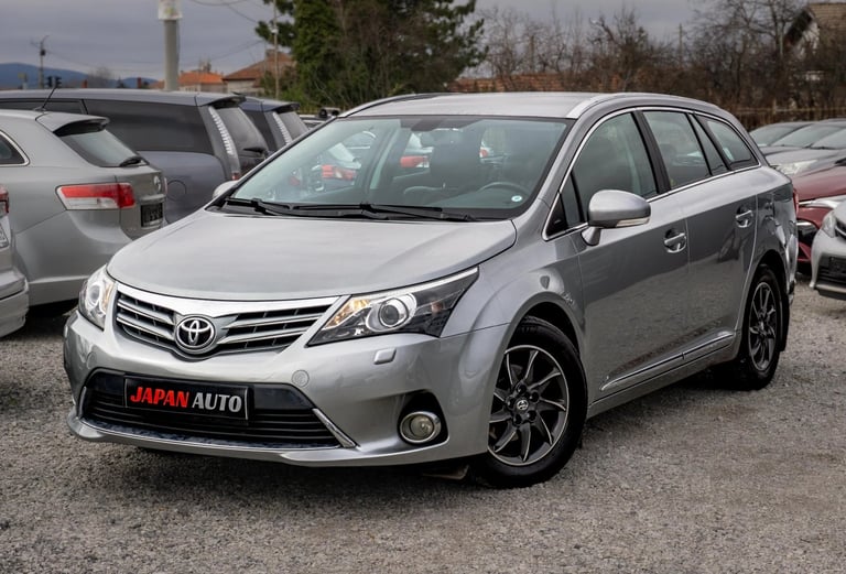 Silver Toyota minivan parked in a car lot with other vehicles visible in the background