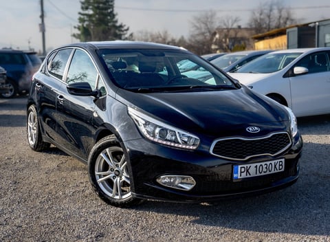 Black Kia compact car parked in a dealership lot on a sunny day