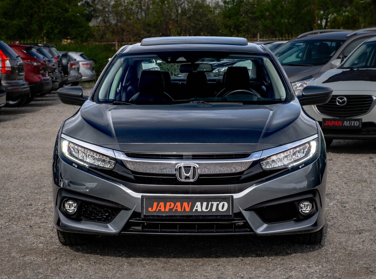 Silver Honda sedan parked in a lot with Japan Auto signage, front view