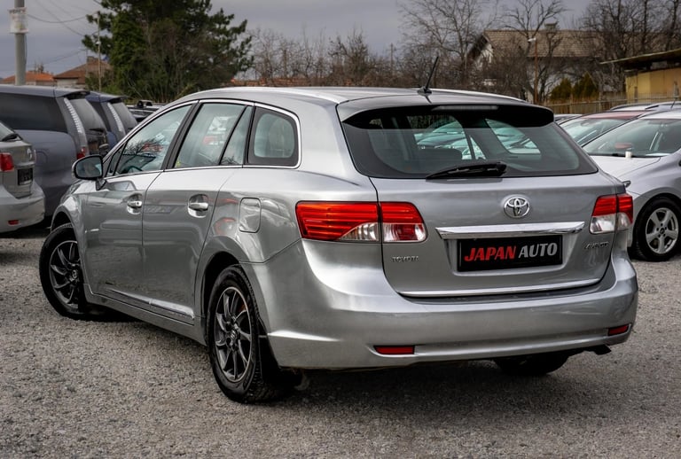 Silver Toyota Auris wagon at a car dealership lot, rear view with red taillights and Japan Auto signage