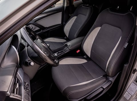 Modern car interior with dark gray and black upholstered seats, steering wheel, and dashboard visible from the drivers side