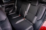 Black and gray car rear seats with textured fabric, red safety belt buckles, and black piping trim