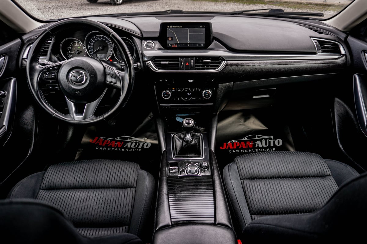 Interior dashboard and steering wheel of a Mazda vehicle with black upholstery and center console display