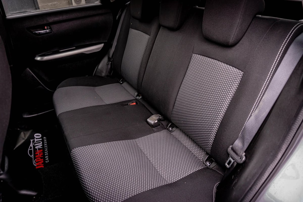 Car interior showing rear seats with gray and black fabric upholstery and seat belt buckles visible