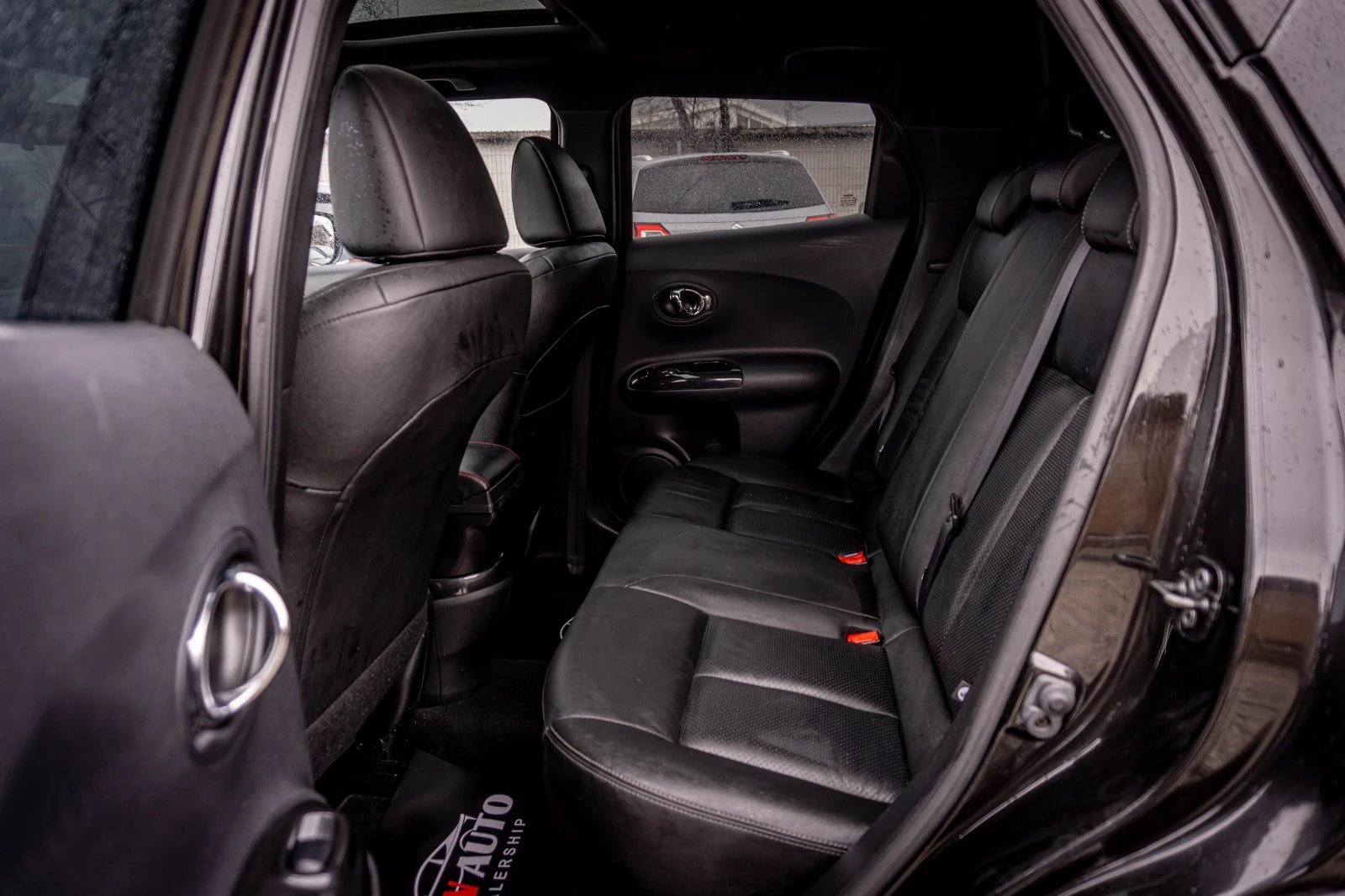 Interior view of a compact vehicle showing the rear seating area with black leather seats and open doors