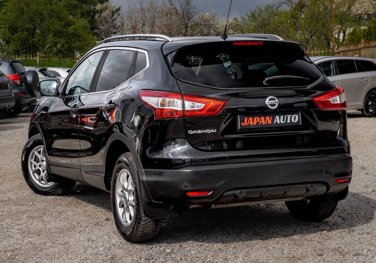 Black Nissan Qashqai SUV with open driver door parked in a lot with trees in background