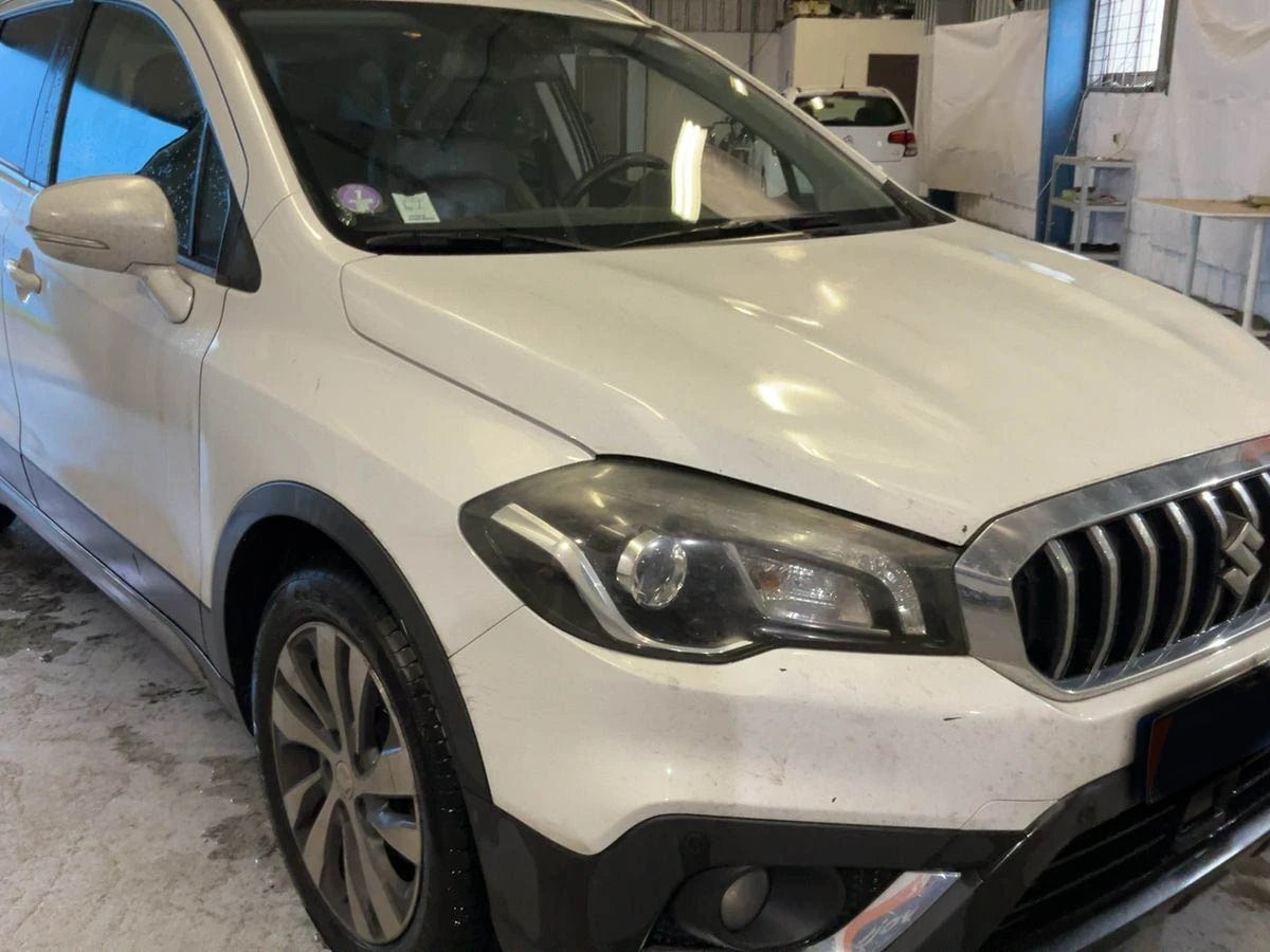 White Mercedes SUV with black grille parked in an indoor garage or workshop setting